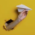 mão saindo da parede segurando um avião de papel