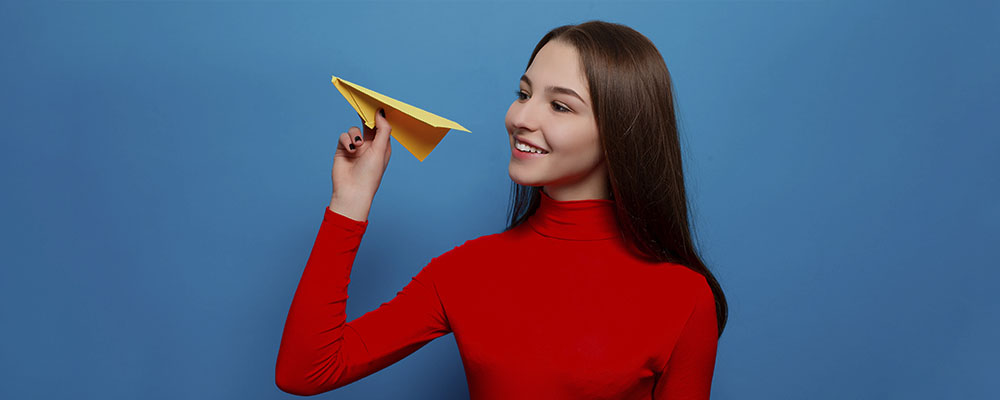 garota atirando um avião de papel e sorrindo