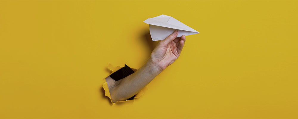 mão saindo da parede segurando um avião de papel