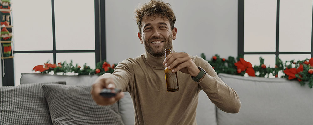 homem tomando uma cerveja enquanto assiste filmes de Natal na Netflix