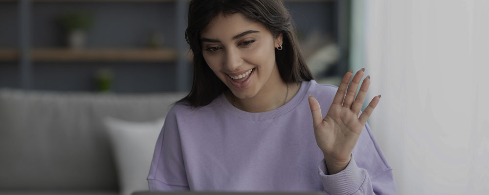 mulher acenando para sua terapeuta por uma chamada de vídeo, pois está fazendo terapia online