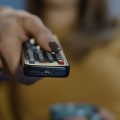 mulher apontando o controle para a TV para assistir séries da Netflix