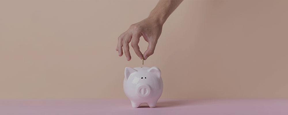 pessoa guardando uma moeda em um cofrinho com formato de porquinho