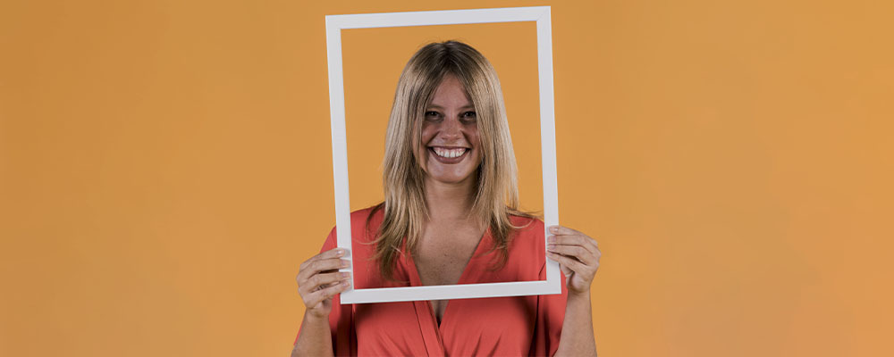 mulher sorrindo segurando uma moldura à frente de seu rosto representando a foto de perfil do WhatsApp