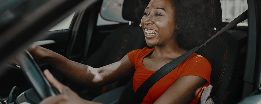 Mulher dirigindo feliz enquanto o Android Auto lê suas mensagens e notificações.