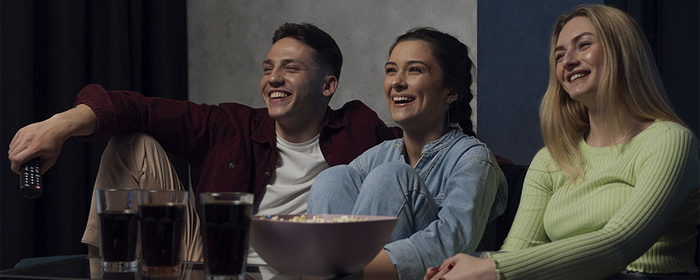 Amigos rindo ao assistir filmes de comédia na Netflix.