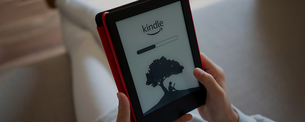 Mulher segurando seu Kindle com a tela de carregamento inicial do Amazon Kindle.
