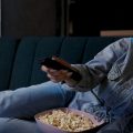 Mulher assistindo os lançamentos da Netflix de junho de 2024 enquanto come pipoca.