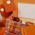 Notebook em meio a vários itens de compra, como carrinho de mercado, carteiras e sacolas, todos na cor laranja remetendo à Shopee.