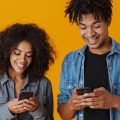 Casal usando celulares Android e sorrindo.