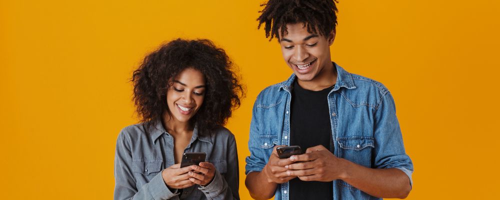 Casal usando celulares Android e sorrindo.