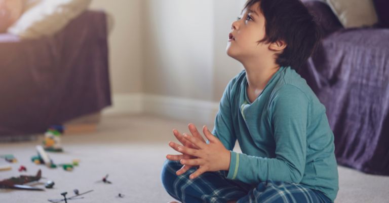 Criança com autismo sentada no chão da sala assistindo TV.