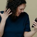 Mulher brava olhando para o celular após perceber que caiu no golpe do Pix.