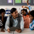 Professor com um tablet ensinando coisas aos seus alunos com a ajuda da tecnologia.