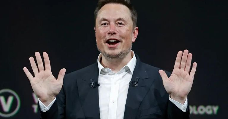 Elon Musk com as mãos erguidas.