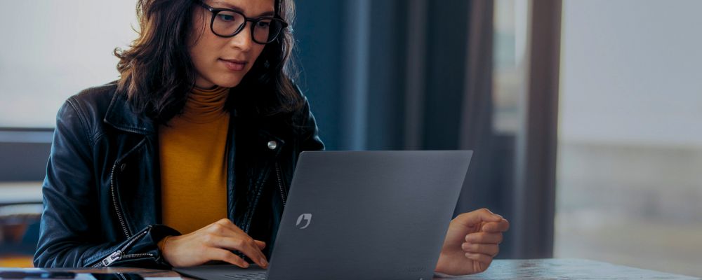 Mulher trabalhando com notebook corporativo da Positivo.