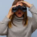 Mulher com binóculo fazendo alusão às buscas no Google.