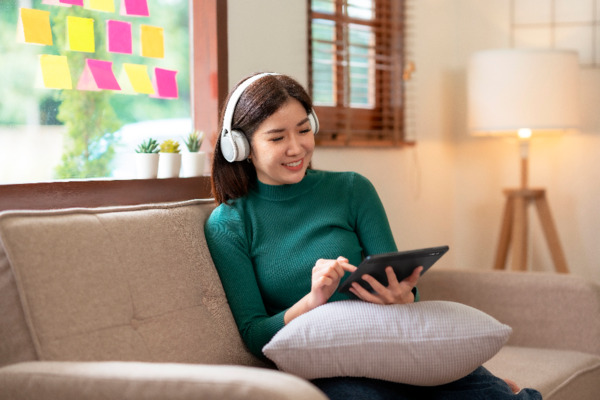 Mulher usando um tablet Positivo Vision TAB 7 e headphones bluetooth.
