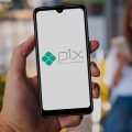 Mulher segurando um celular da Postivo com o logo do Pix aparecendo na tela.