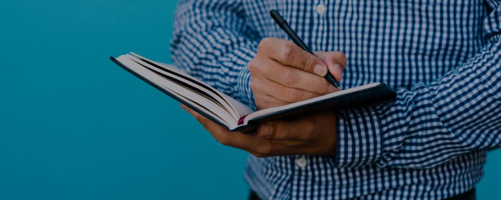 Homem fazendo anotações em um caderno.