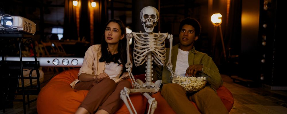 Casal assistindo os lançamentos da Netflix para outubro de 2024 com uma caveira.