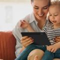 Mãe usando um tablet Positivo Vision 7 para brincar com sua filha.