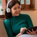 Mulher usando um tablet Positivo Vision 7 para estudar com fones de ouvido.