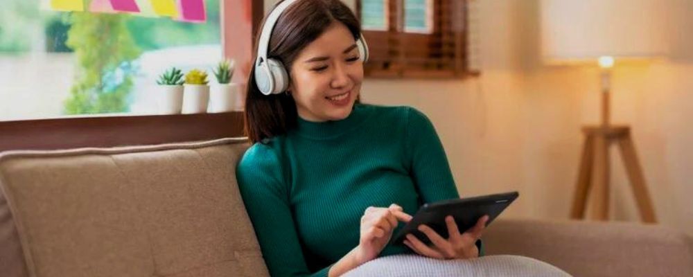 Mulher usando um tablet Positivo Vision 7 para estudar com fones de ouvido.