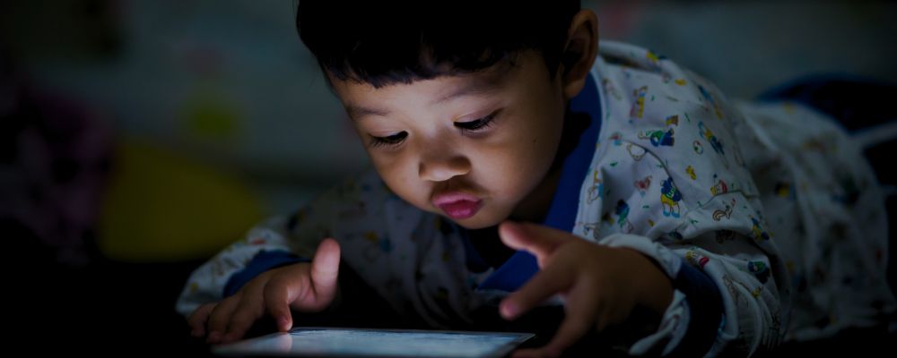 Criança usando apps de leitura em um tablet.