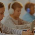 Crianças usando notebooks e tablets para fazer anotações durante as aulas.