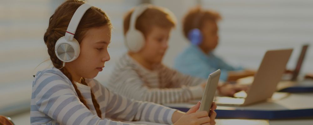 Crianças usando notebooks e tablets para fazer anotações durante as aulas.