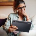 Mulher lendo na sala em seu tablet Positivo.