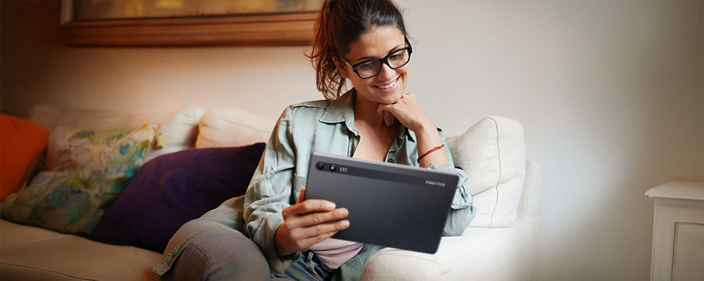 Mulher lendo na sala em seu tablet Positivo.