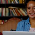 Moça sorrindo ao estudar com notebooks.