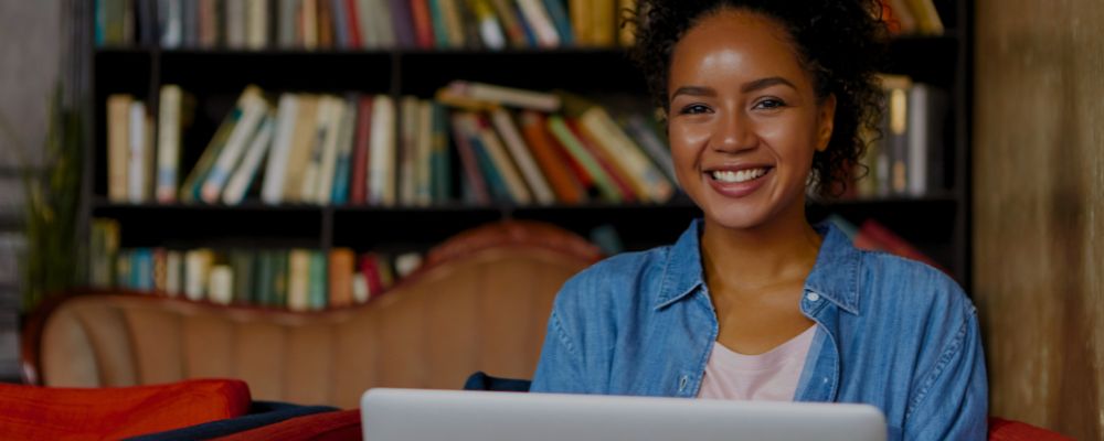 Moça sorrindo ao estudar com notebooks.