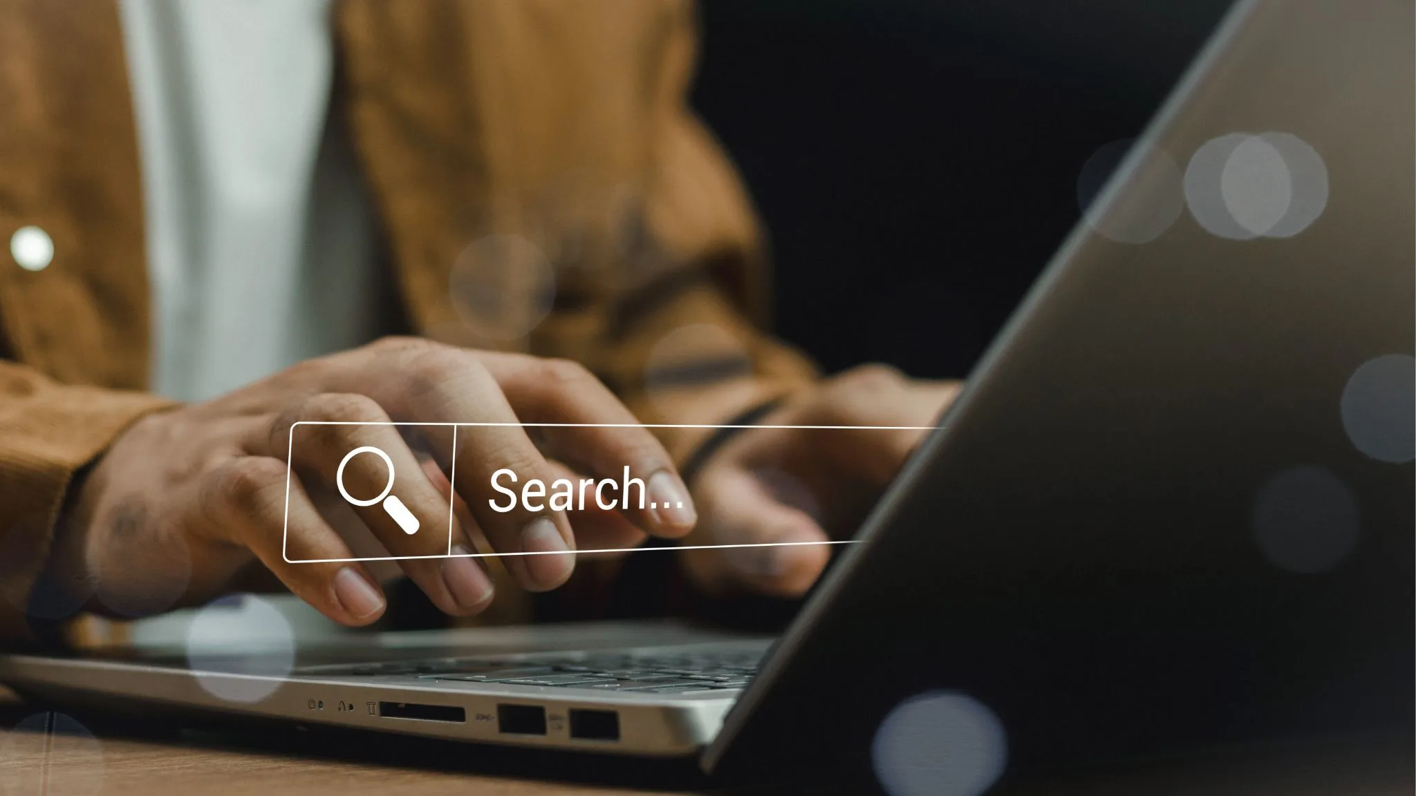 homem pesquisando no notebook, balão escrito "Search"