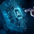 Mão tocando um chip de inteligência artificial (AI) brilhante em um circuito eletrônico azul futurista, simbolizando inovação, tecnologia e a interação humana com sistemas de IA. O fundo escuro com elementos digitais abstratos reforça o conceito de computação avançada e o futuro da tecnologia.
