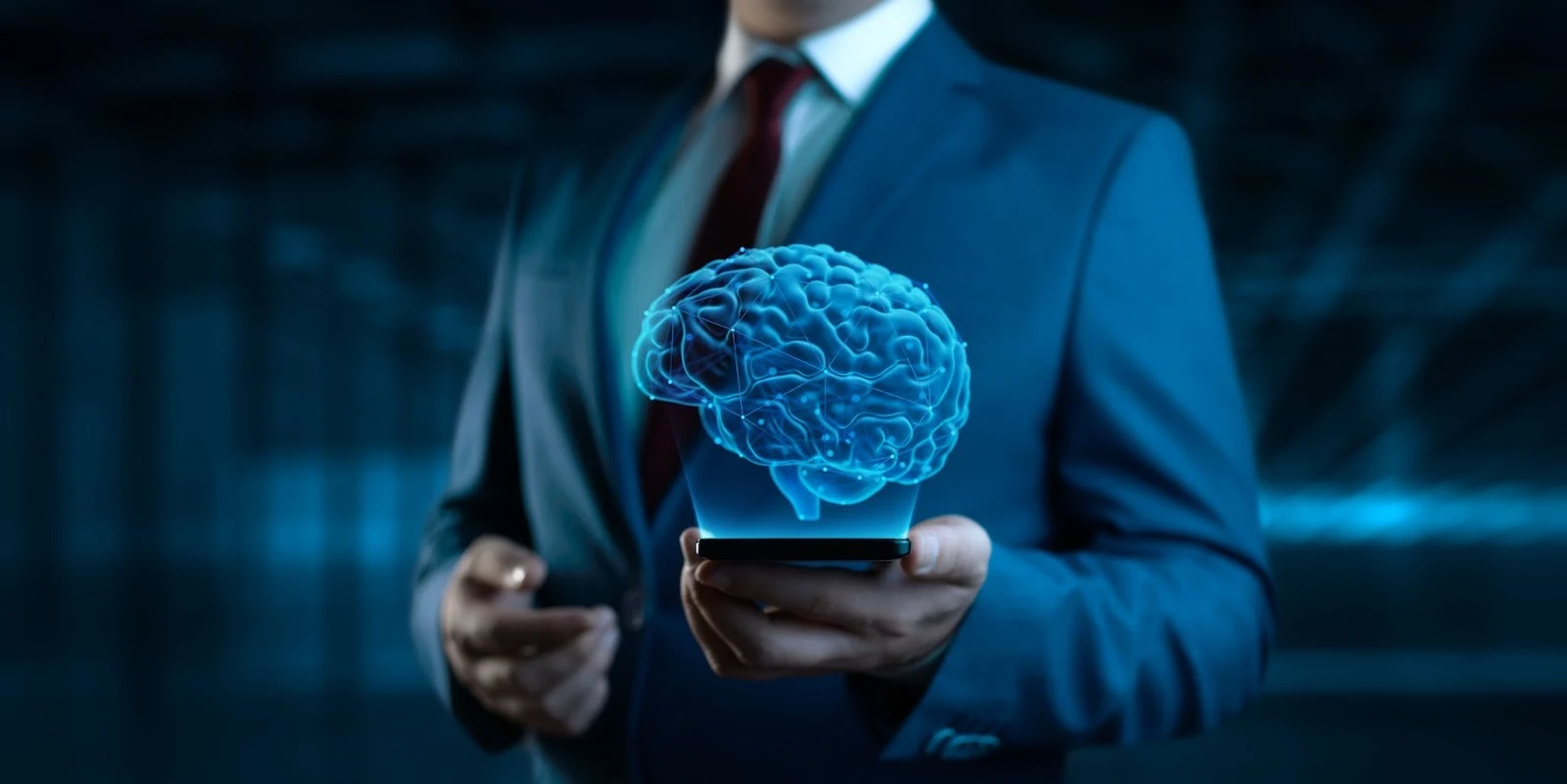 Executivo em terno azul escuro e gravata vermelha segurando um smartphone, do qual emerge uma projeção holográfica azul brilhante de um cérebro humano com conexões neurais. A imagem simboliza inteligência artificial (IA), tecnologia avançada, inovação, neurociência e o poder do pensamento estratégico no mundo dos negócios.