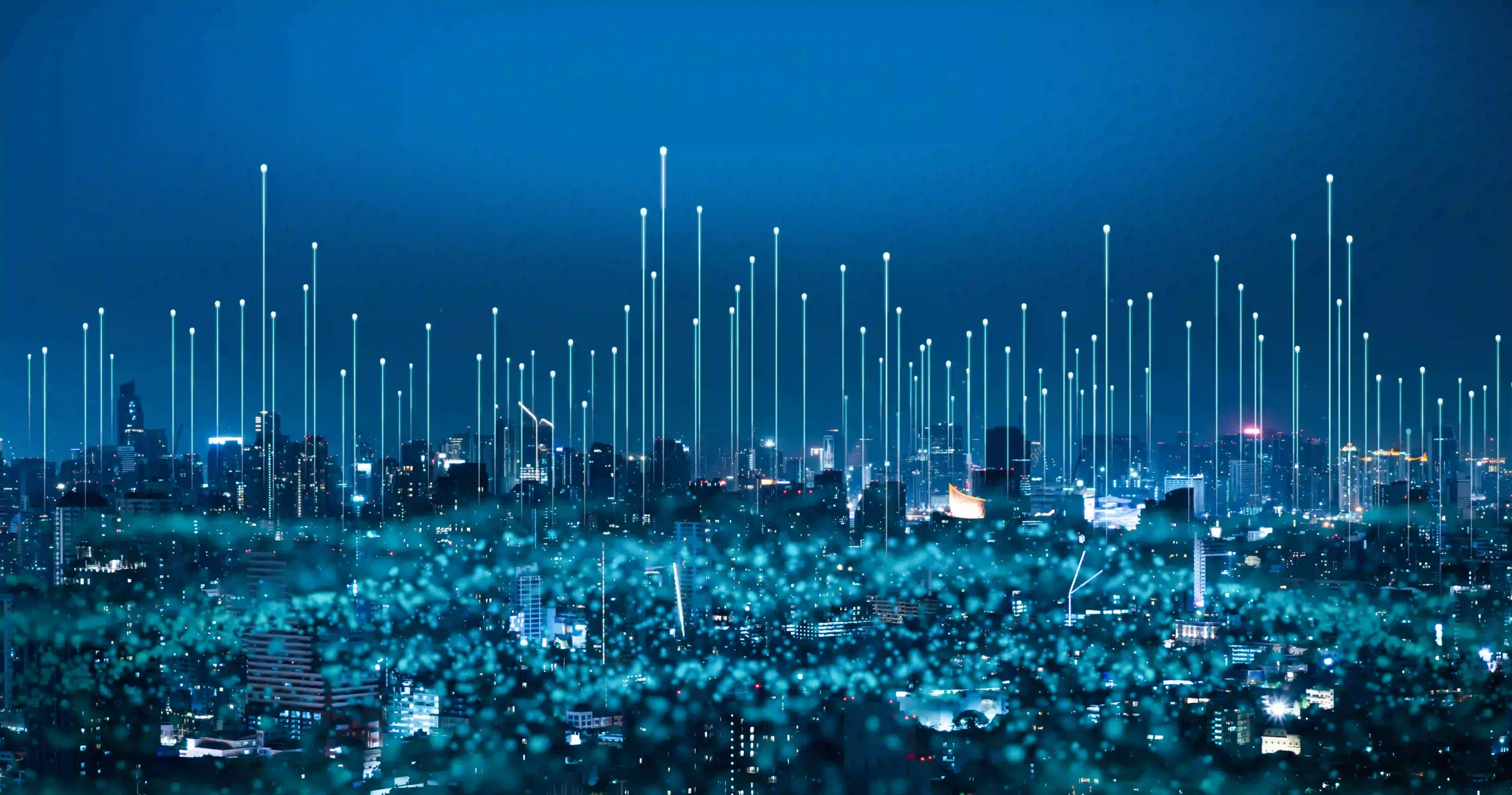 Paisagem urbana noturna com prédios e arranha-céus iluminados, sobreposta por linhas de luz verticais e pontos brilhantes, simbolizando rede de dados, conectividade tecnológica e comunicação global em uma cidade inteligente.