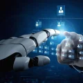 Mão robótica branca e mão humana interagindo com um organograma digital holográfico azul, exibindo uma rede de perfis de pessoas. A imagem simboliza a colaboração entre inteligência artificial e gestão de recursos humanos, automação de processos ou o futuro do trabalho com tecnologia avançada.