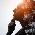 Silhueta de perfil de uma mulher com óculos em pose reflexiva, com uma sobreposição digital de gráficos de dados, mapas, ícone de cérebro iluminado e elementos de inteligência artificial e tecnologia.